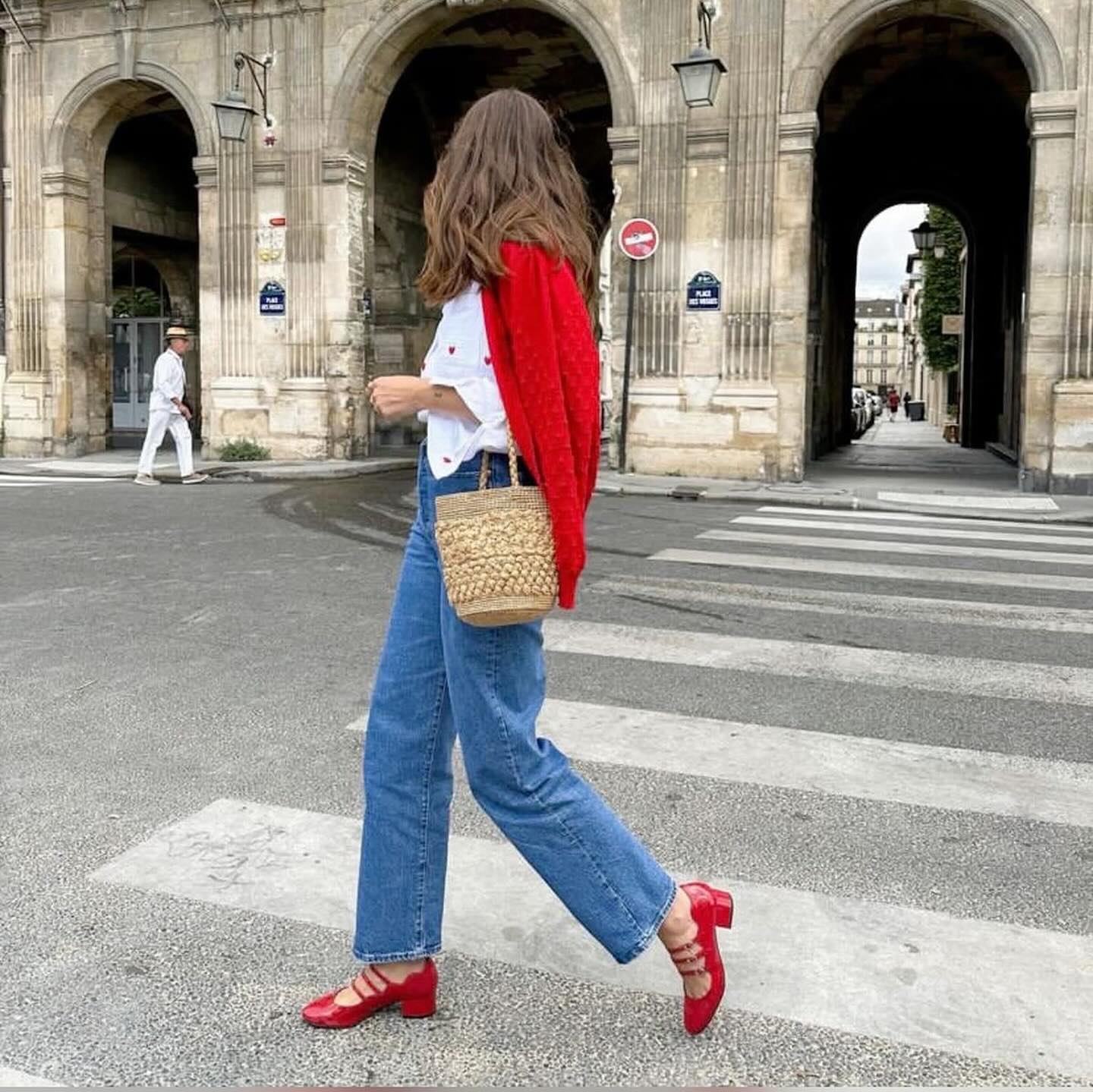 Modelo usando calça jeans e camisa branca com sapato Mary Jane vermelho.