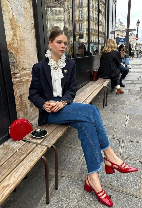 Modelo usando calça jeans e blazer com sapato vermelho.