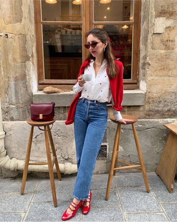 Modelo usando calça jeans e camisa branca com sapato Mary Jane vermelho.