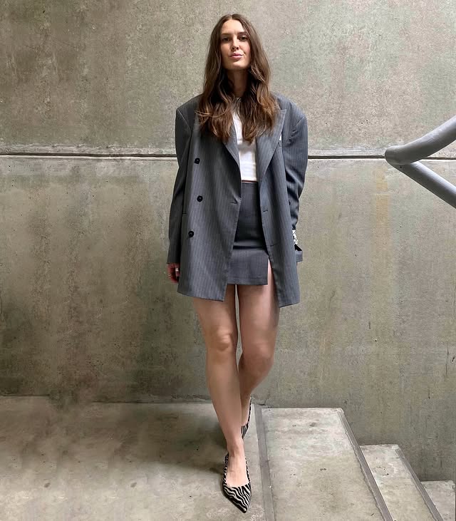 Modelo usando blazer oversized e mini saia de alfaiataria, um look para trabalhar no calor elegante.